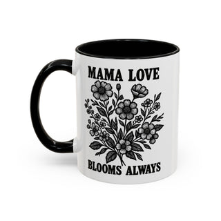 White mug with black handle and interior, featuring floral design and text "MAMA LOVE BLOOMS ALWAYS".