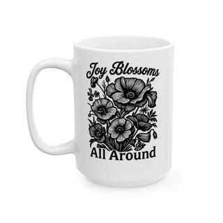 White mug with black line drawing of poppies and "Joy Blossoms All Around" text.