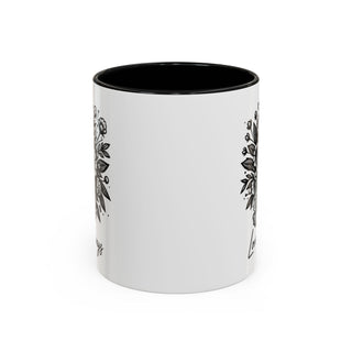 White ceramic mug with black floral design and text.