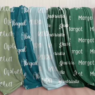 Custom name blankets in earthy tones including olive, teal, light blue, and forest green. Includes soft sherpa or minky backing and gentle name font overlays.
