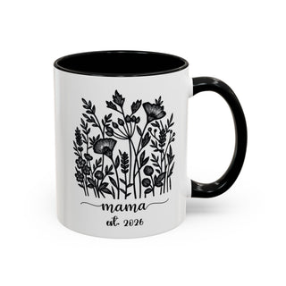 White mug with black rim and handle, featuring floral illustration and "mama est. 2026".