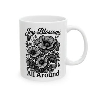 White mug with black poppy illustration and "Joy Blossoms All Around" text.
