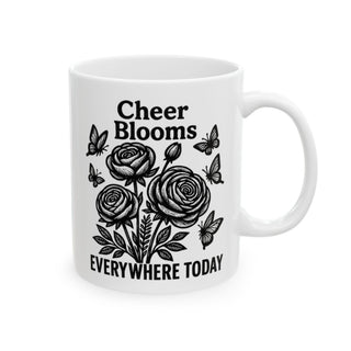 White mug with black floral design and text "Cheer Blooms Everywhere Today".