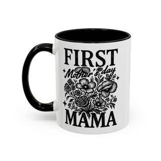 White mug with black handle and rim, "First Mother's Day Mama" text and floral design.
